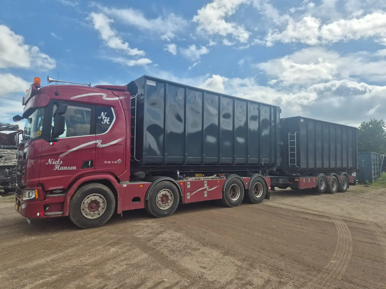 Containerbil med åben container og kærre med endnu en container