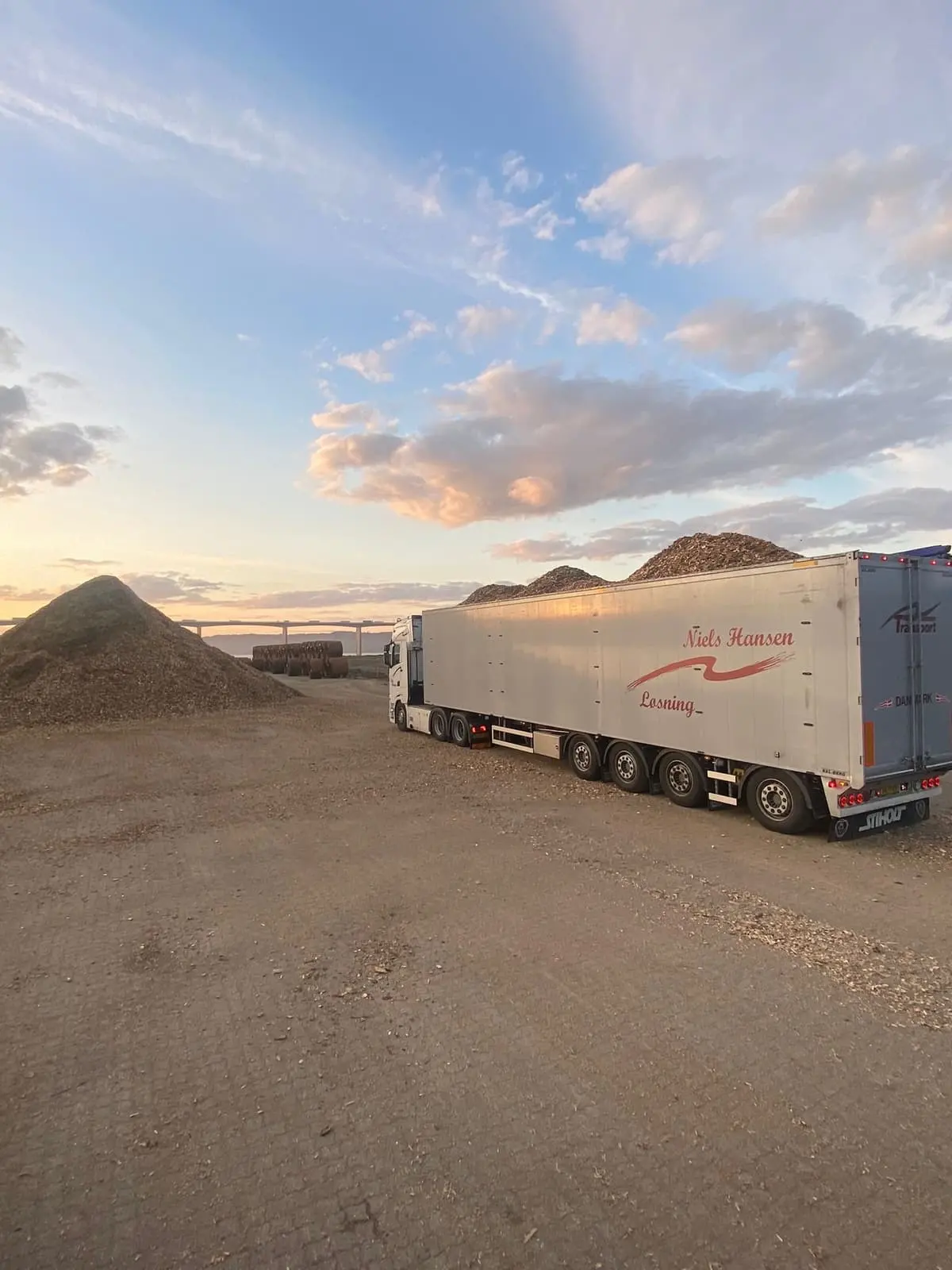 Trailer fyldt til randen med flis på pladsen i aftenlyset