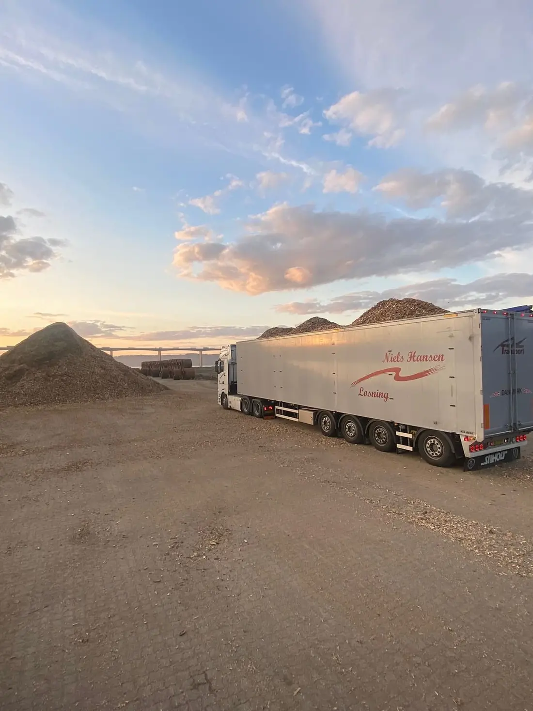 Trailer fyldt til randen med flis på pladsen i aftenlyset