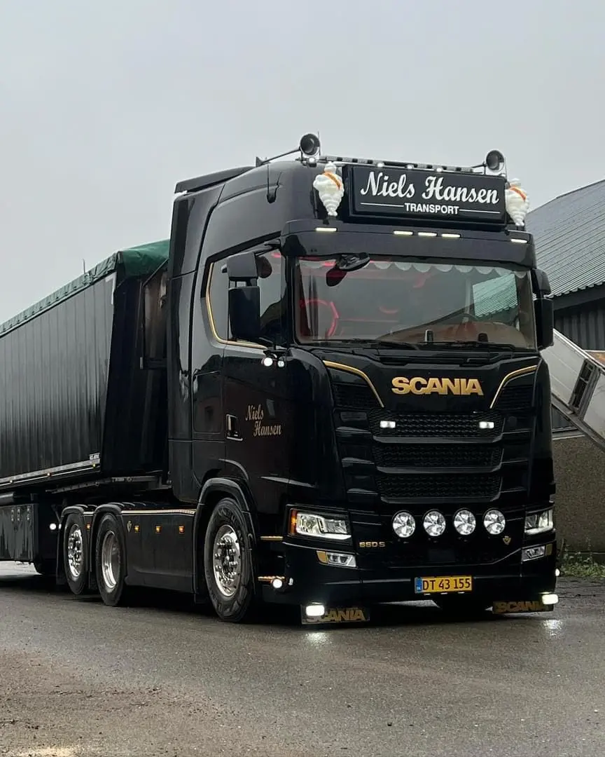 Sort lastbil med presenningtrailer på våd asfalt i gråvejr