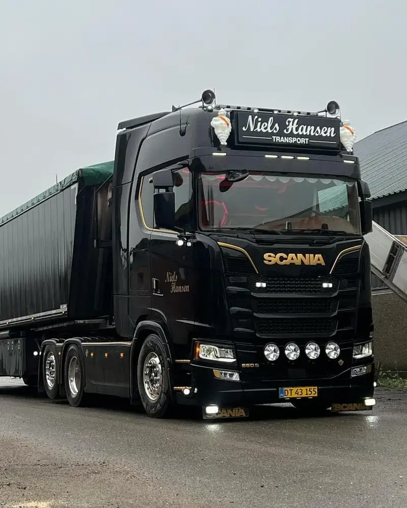 Sort lastbil med presenningtrailer på våd asfalt i gråvejr