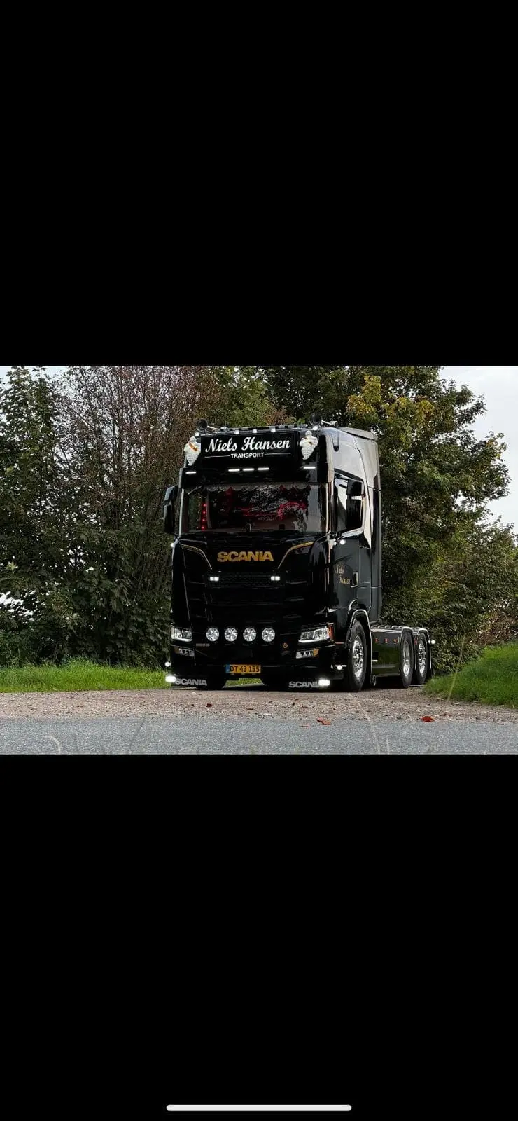 Sort lastbil uden trailer med tændte lygter holdt ind til vejkanten