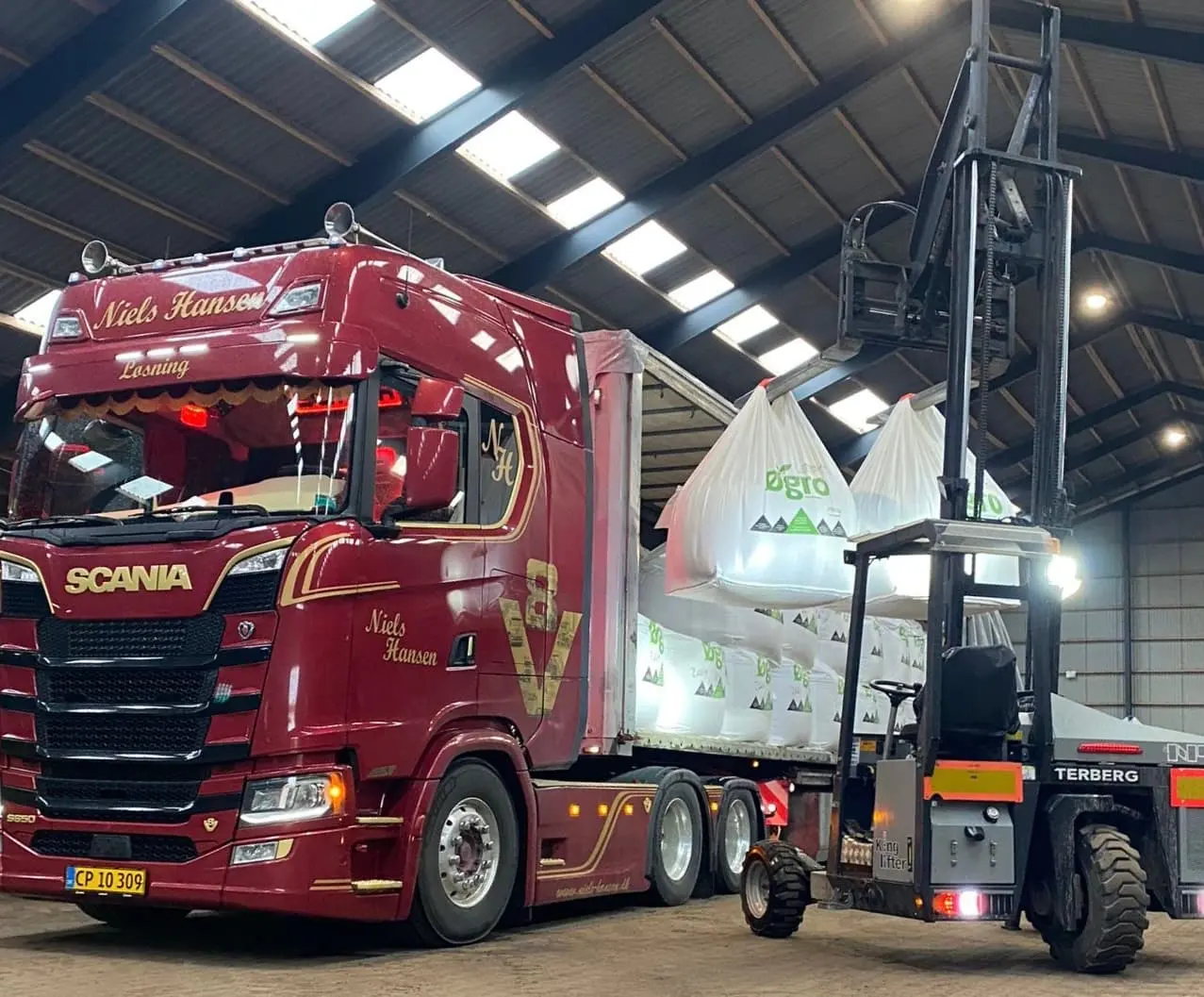 Big bags løftes ind i traileren med truck inde i lagerhallen
