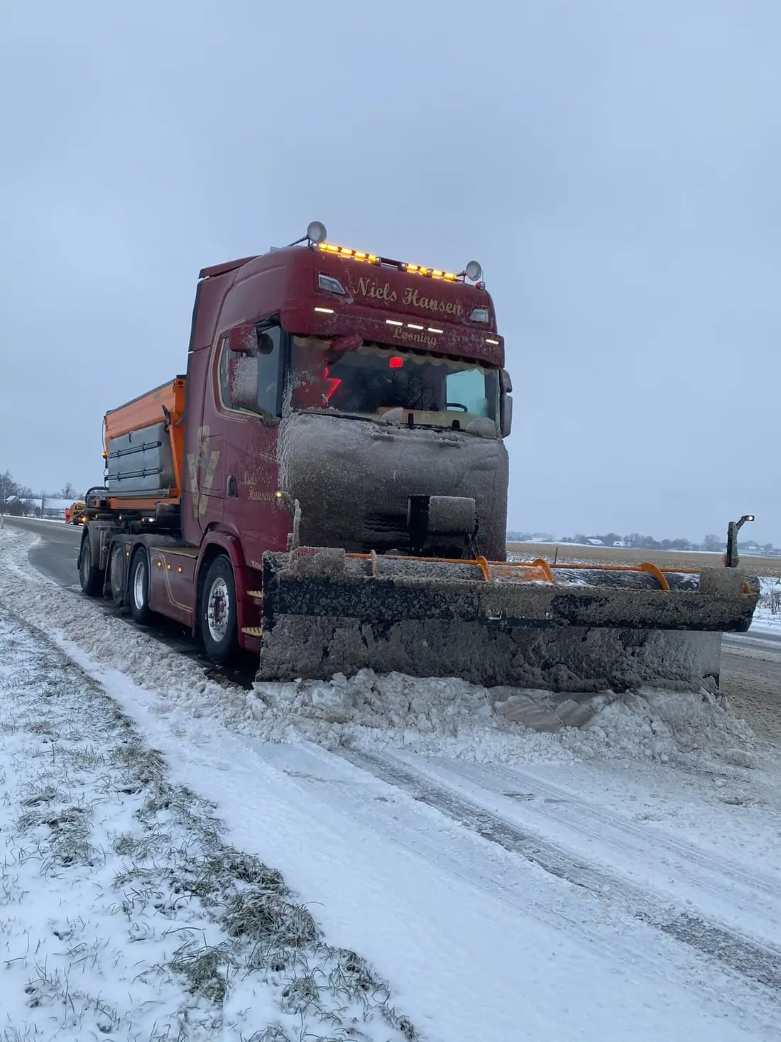 Sneplov og spreder monteret på lastbilen ude på den snedækkede landevej