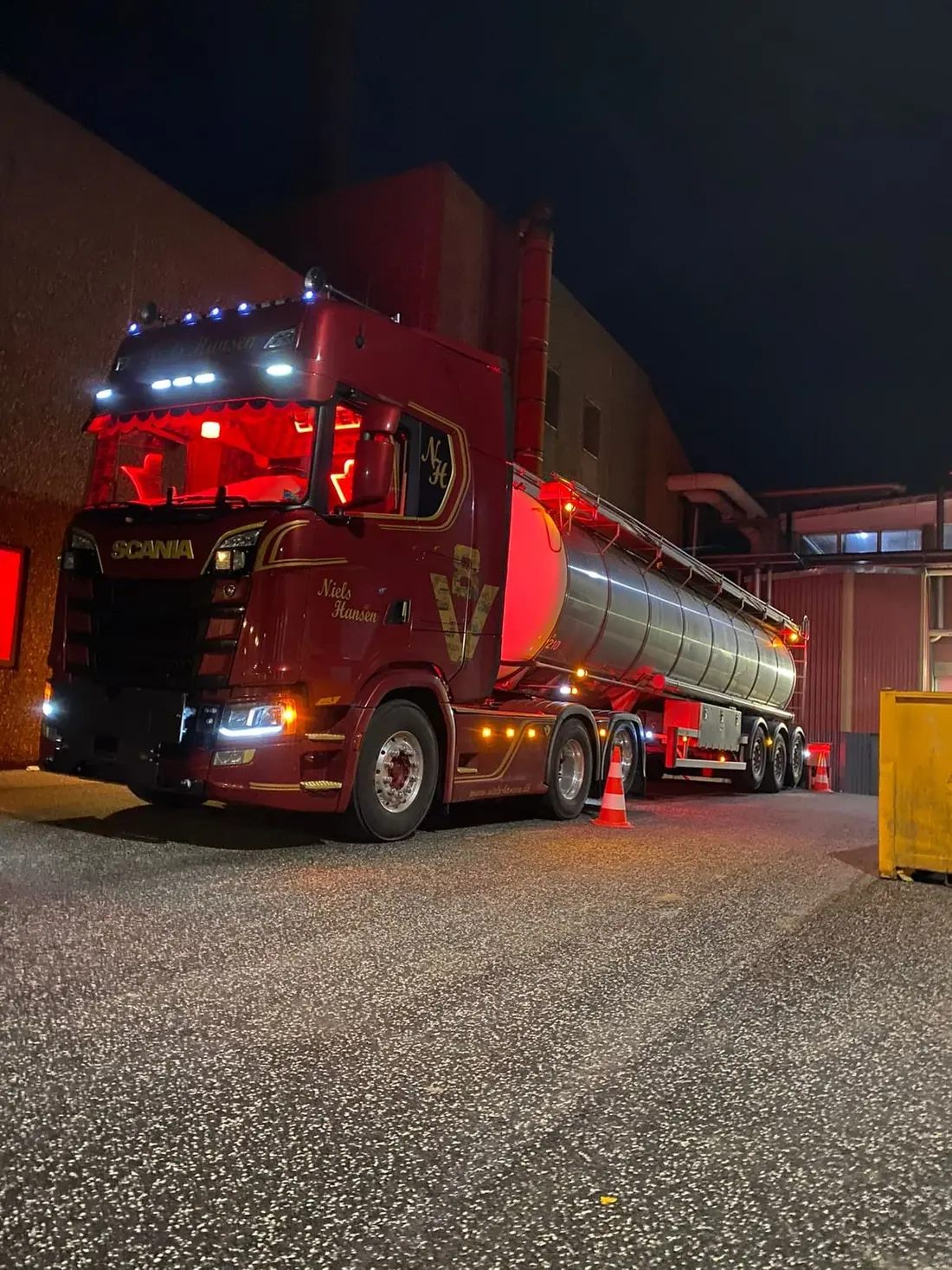 Lastbil med blank ståltanktrailer holder ved industribygningen om natten