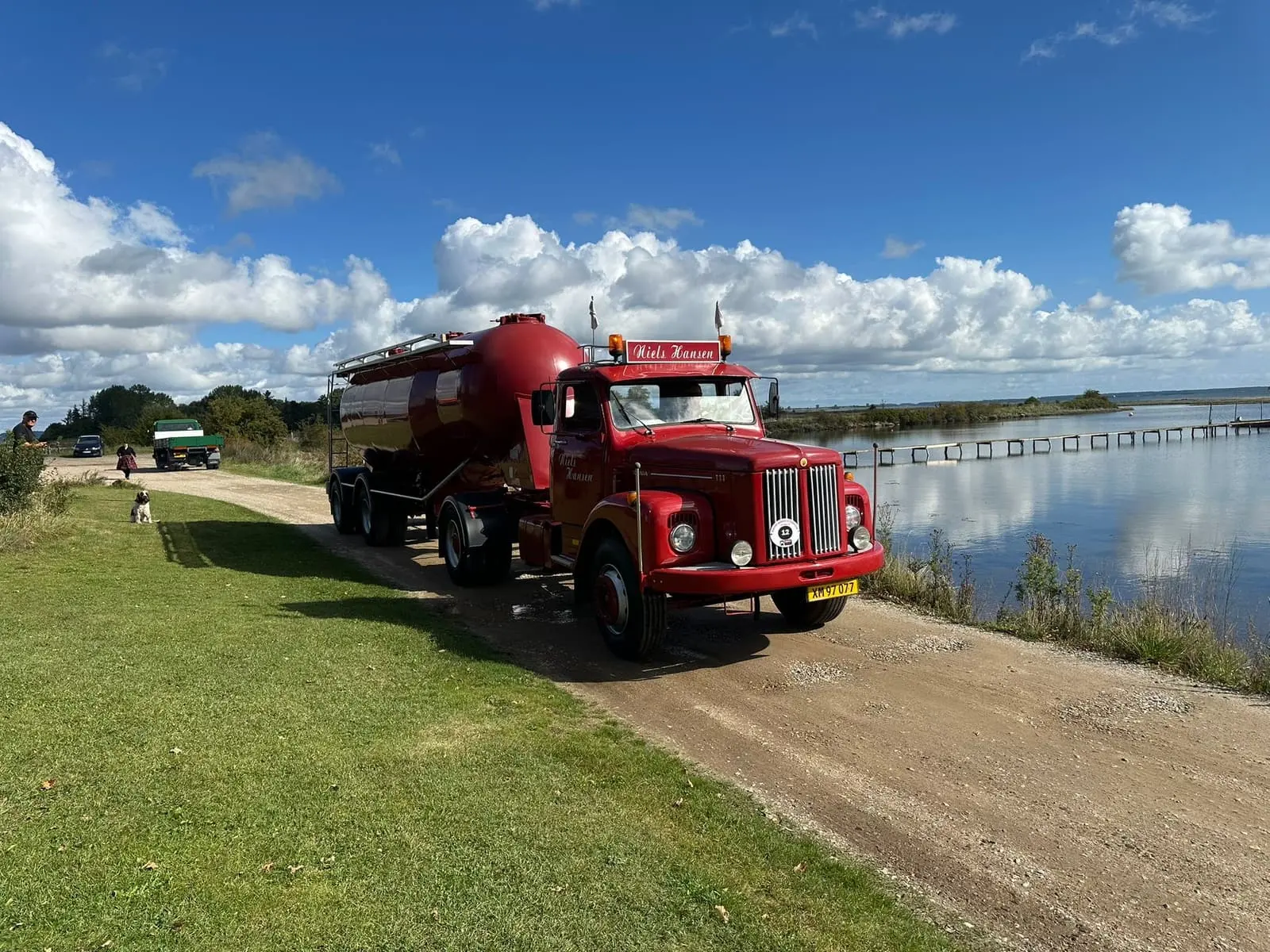 Veteranlastbil med blank silotrailer på grusvejen ude ved vandet